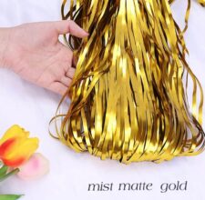 Matte gold fringe party tassel decoration held by hand