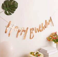 Rose-gold 'Happy Birthday' script banner hanging on wall