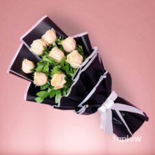 Multiple pale roses in a black-and-pink gift wrap bouquet