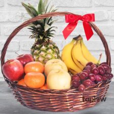 Large wicker fruit basket with pineapple, bananas, apples, oranges and a decorative red bow.