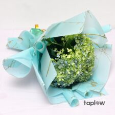 Bouquet of small white and green filler flowers wrapped in blue paper