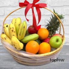 Packaged fresh fruit and grocery items arranged for a gift hamper presentation.