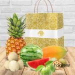 Assorted tropical fruits displayed with a branded gift bag and watermelon slices.