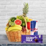Luxury fruit hamper including pineapple, Cadbury Dairy Milk chocolate and an energy drink.