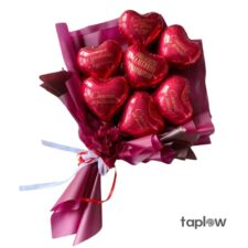 Bouquet of small red heart-shaped foil balloons wrapped in maroon paper with ribbon