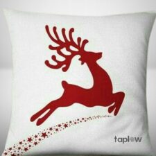 White cushion with red reindeer silhouette and trailing stars