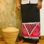 Black sarong with red spiral border beside woven basket