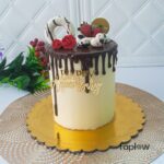 Tall white-and-chocolate drip cake decorated with raspberries and chocolate squares.