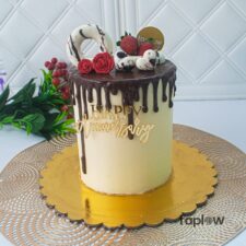 Tall white-and-chocolate drip cake decorated with raspberries and chocolate squares.