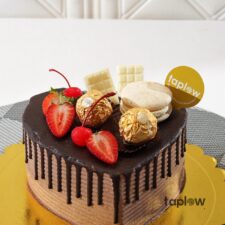 Heart-shaped chocolate cake topped with strawberries, white chocolate pieces and Ferrero Rocher.