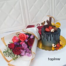 Mixed flower bouquet beside small chocolate drip cake