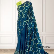 Teal printed saree on mannequin with circular motif â€” product image.