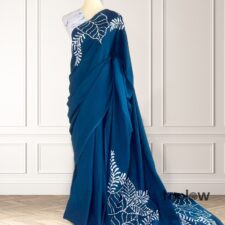 Dark teal saree with white leaf-print pallu on mannequin
