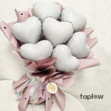 Bouquet of white heart-shaped foil balloons with pink ribbon and paper wrap